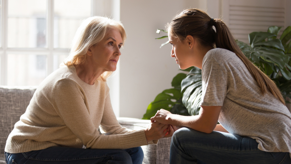 An older and younger woman holding hands while having a deep conversation | Source: Shutterstock