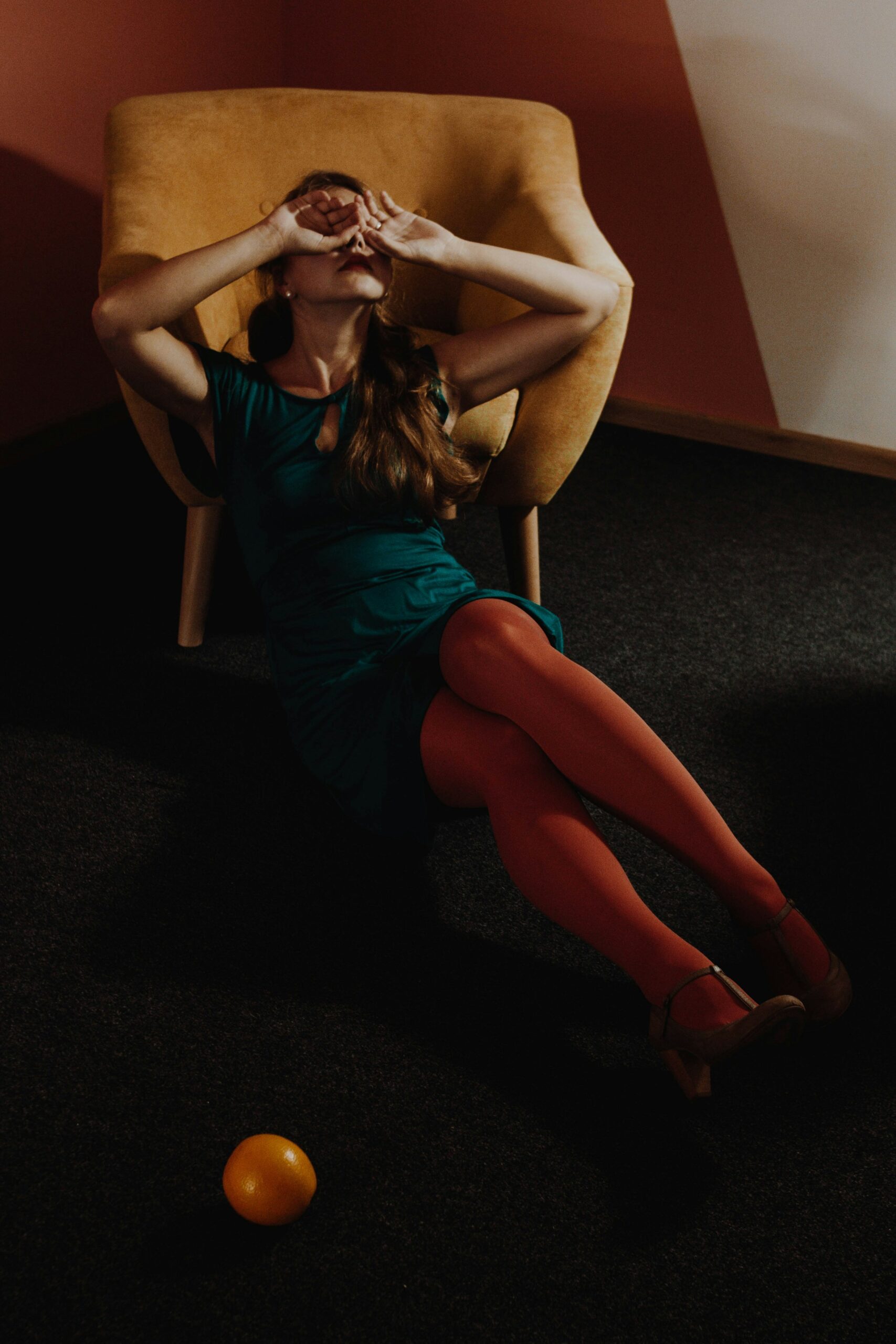 A distressed woman leaning against a sofa covering her face with her hands | Source: Unsplash