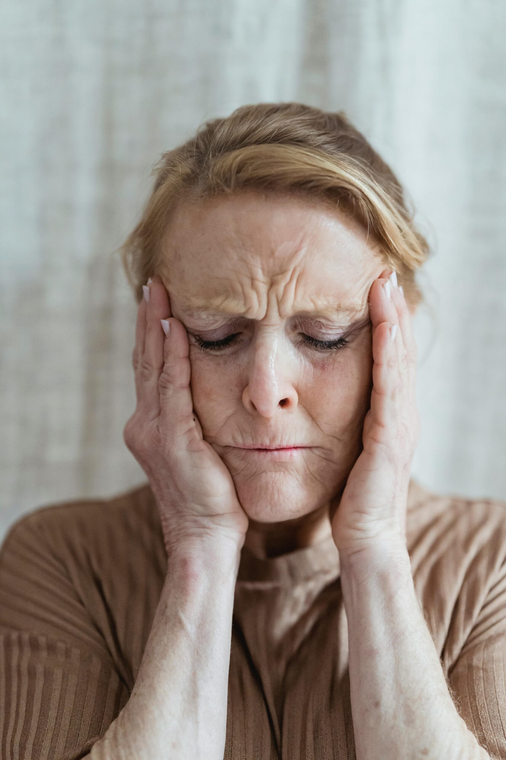 A woman holding her head in her hands | Source: Pexels