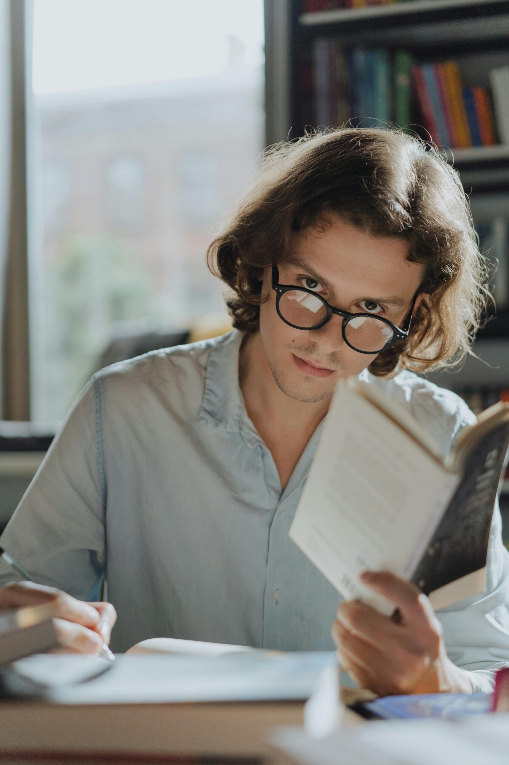 A man reading a book and writing notes while looking at someone | Source: Pexels