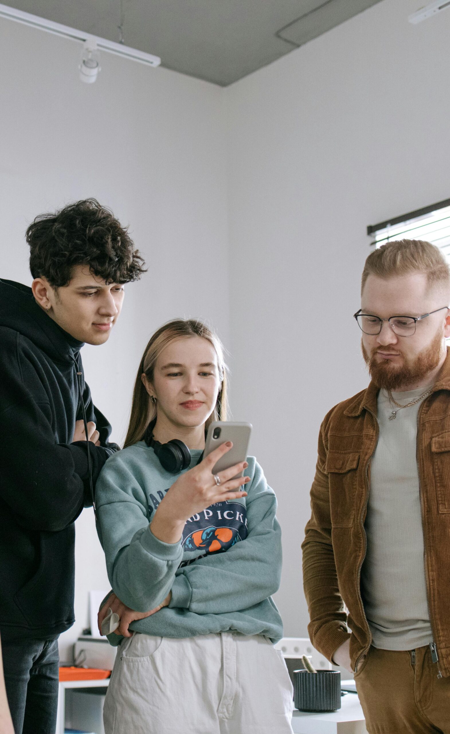 A woman and two man looking at a phone while plotting something | Source: Pexels