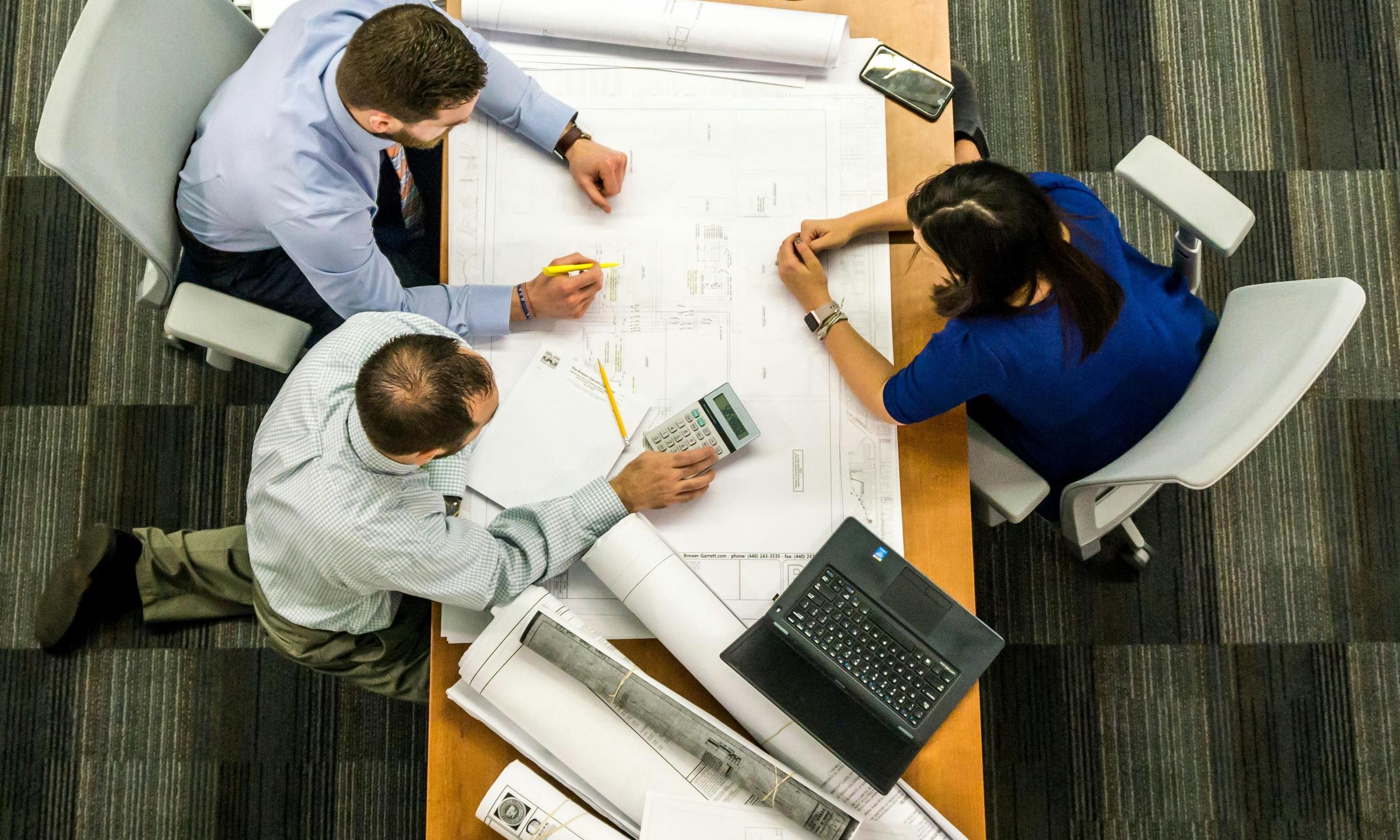 A woman and two men consult across a desk | Source: Pexels
