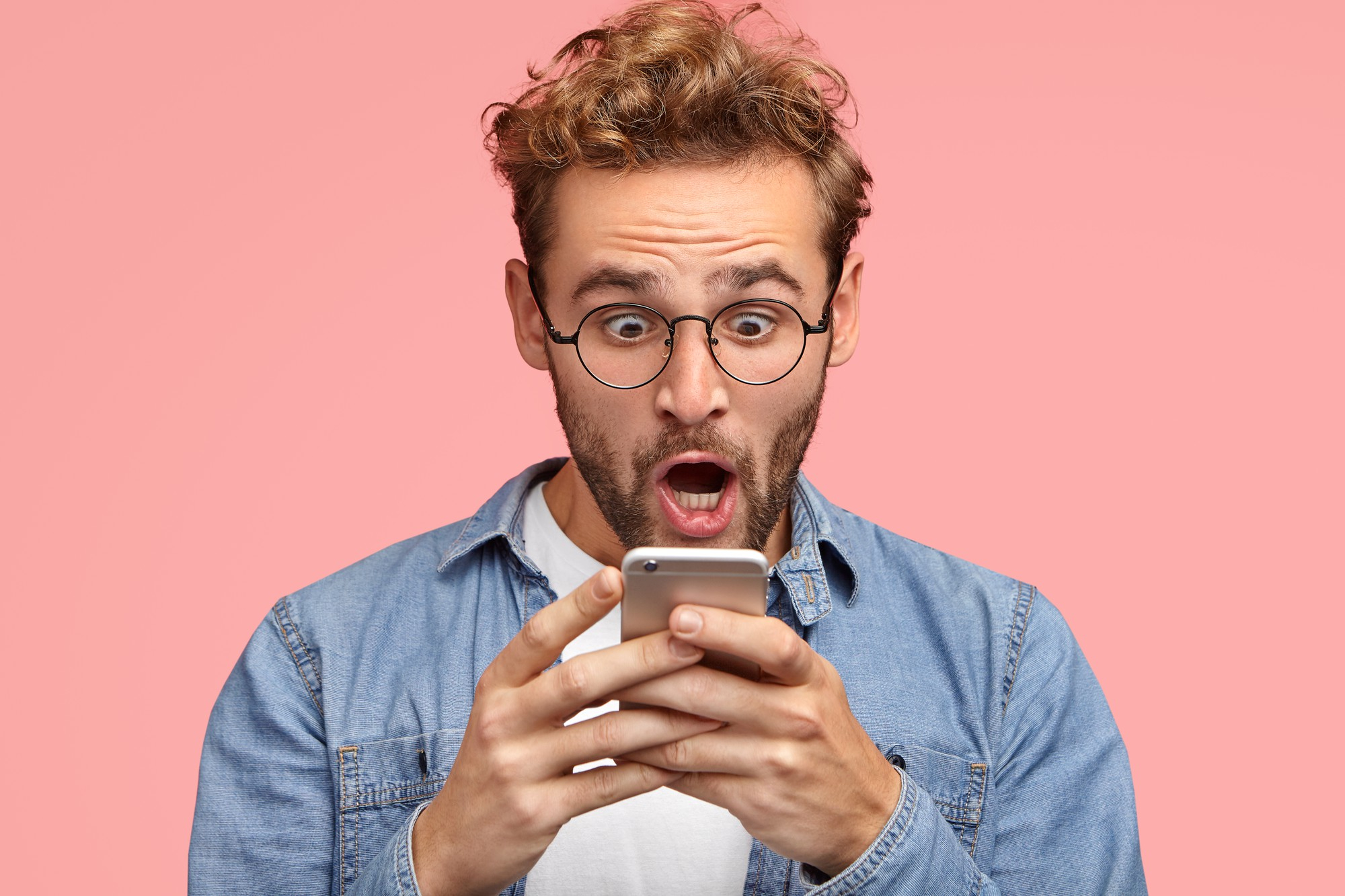 A man reacting in show to something on his phone | Source: Freepik