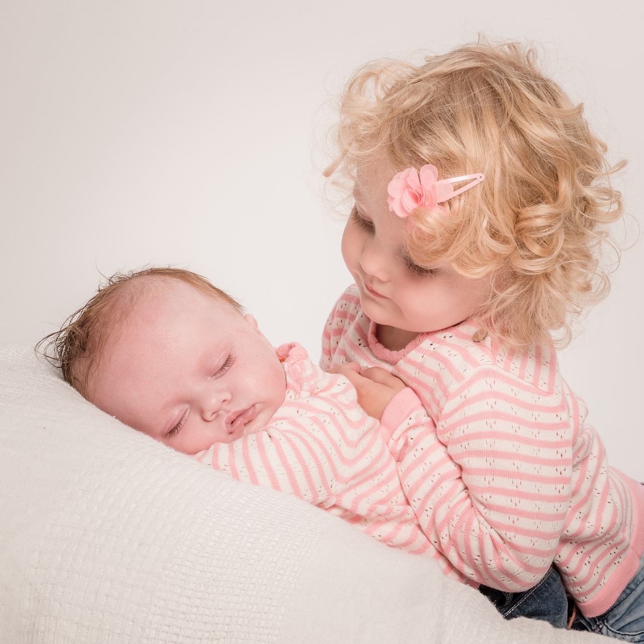 A little girl gazing down at her sleeping baby sister | Source: Pixabay