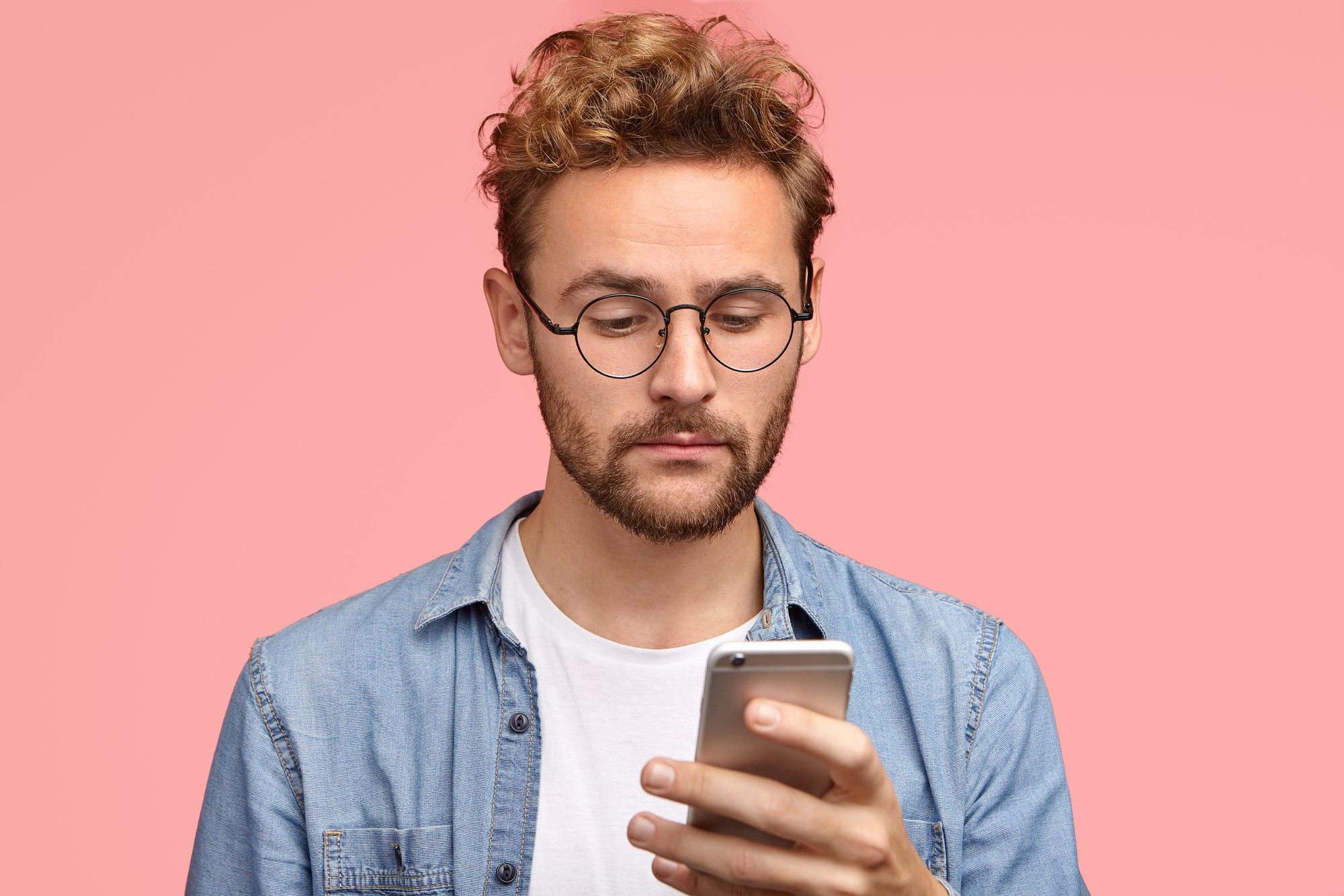 An unhappy-looking man looking at his phone: Freepik