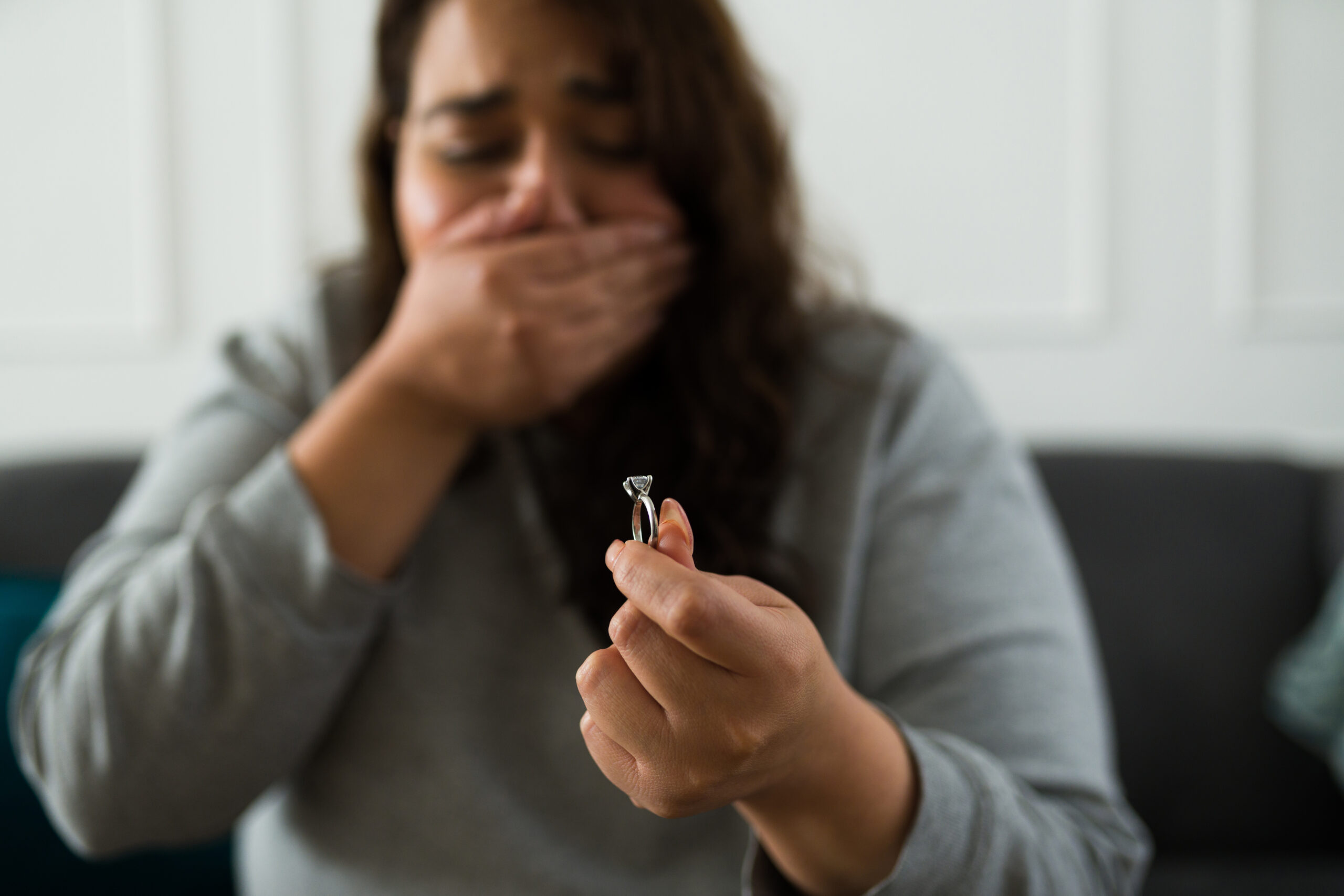 An emotional woman looking at a wedding ring | Source: Getty Images